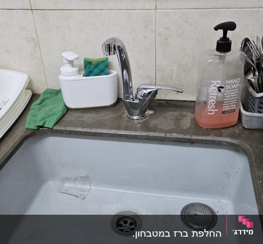 כיור עם ברז, סבון כלים ומגבת ירוקה